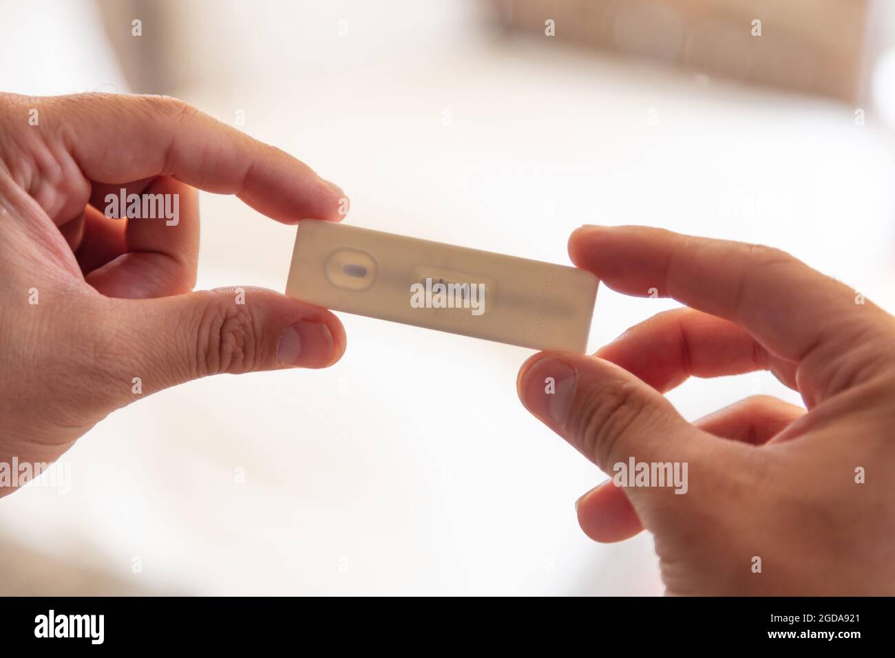 Coronavirus-Selbsttest zu Hause, man Hands mit covid 19 positivem Schnelltest, Kit zum Nachweis von Antikörpern und Immunität. Nahaufnahme, sele Stockfoto