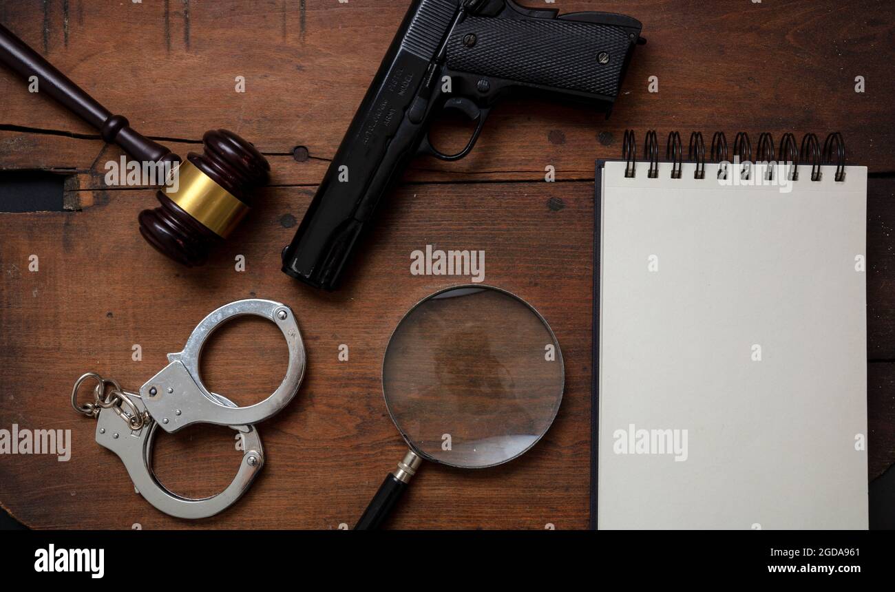 Selbstmordnotiz, Kriminalpolizei-Konzept. Richterklavel, Handfeuerwaffe, Handschellen und ein leerer Notizblock, Gesetz, Verbrechen, Strafe flach lag auf Holzschreibtisch Hintergro Stockfoto