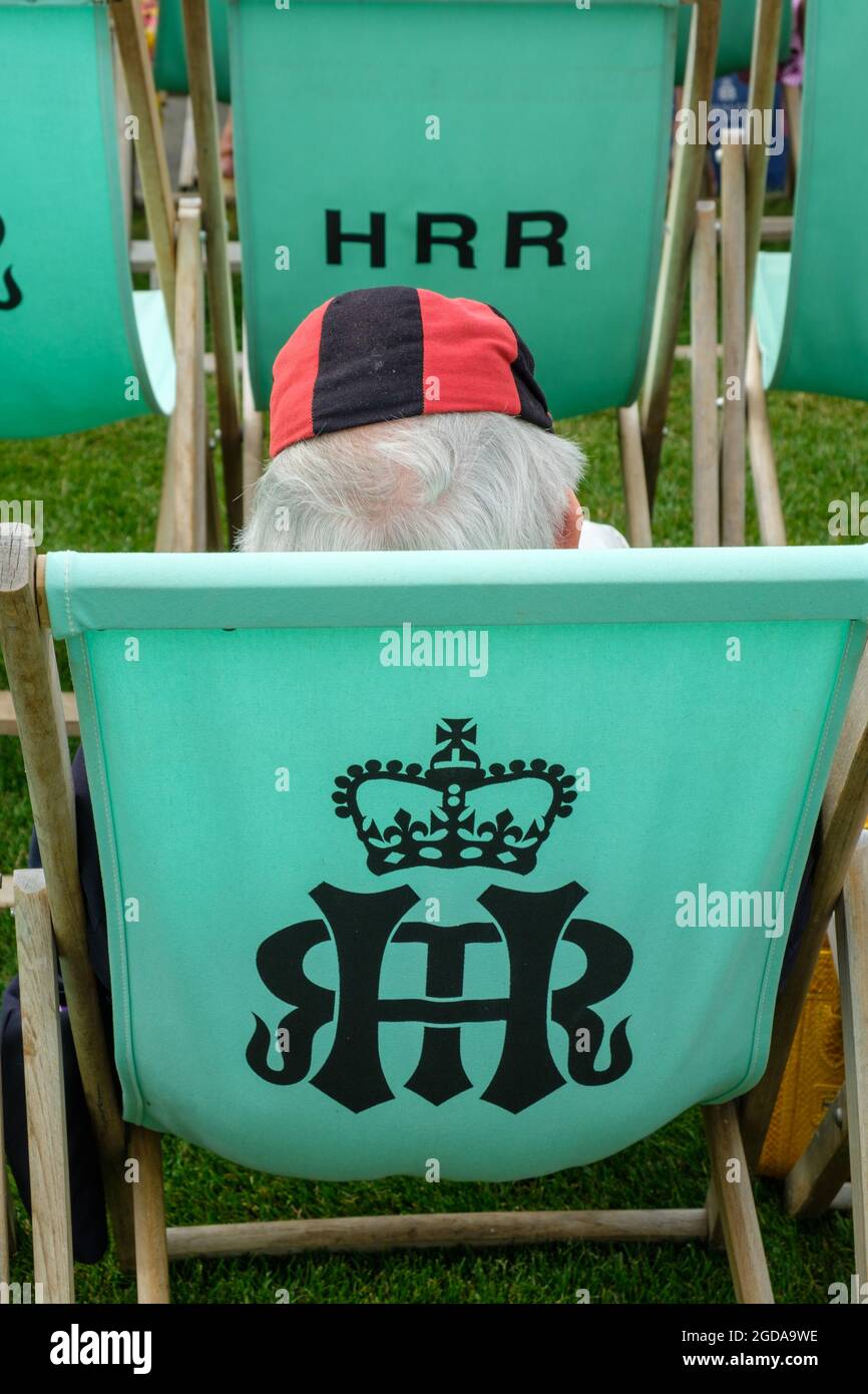Ein Gentleman in einer blau-roten Ruderkappe unter den Liegestühlen der Henley Royal Regatta 2021 Stockfoto