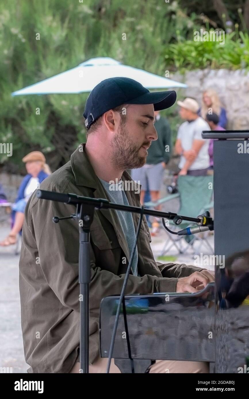 Der zeitgenössische Pianist und Komponist Elliott Jacqués spielt am Trebah Garden Beach in Polgwidden Cove in Cornwall Klavier. Stockfoto