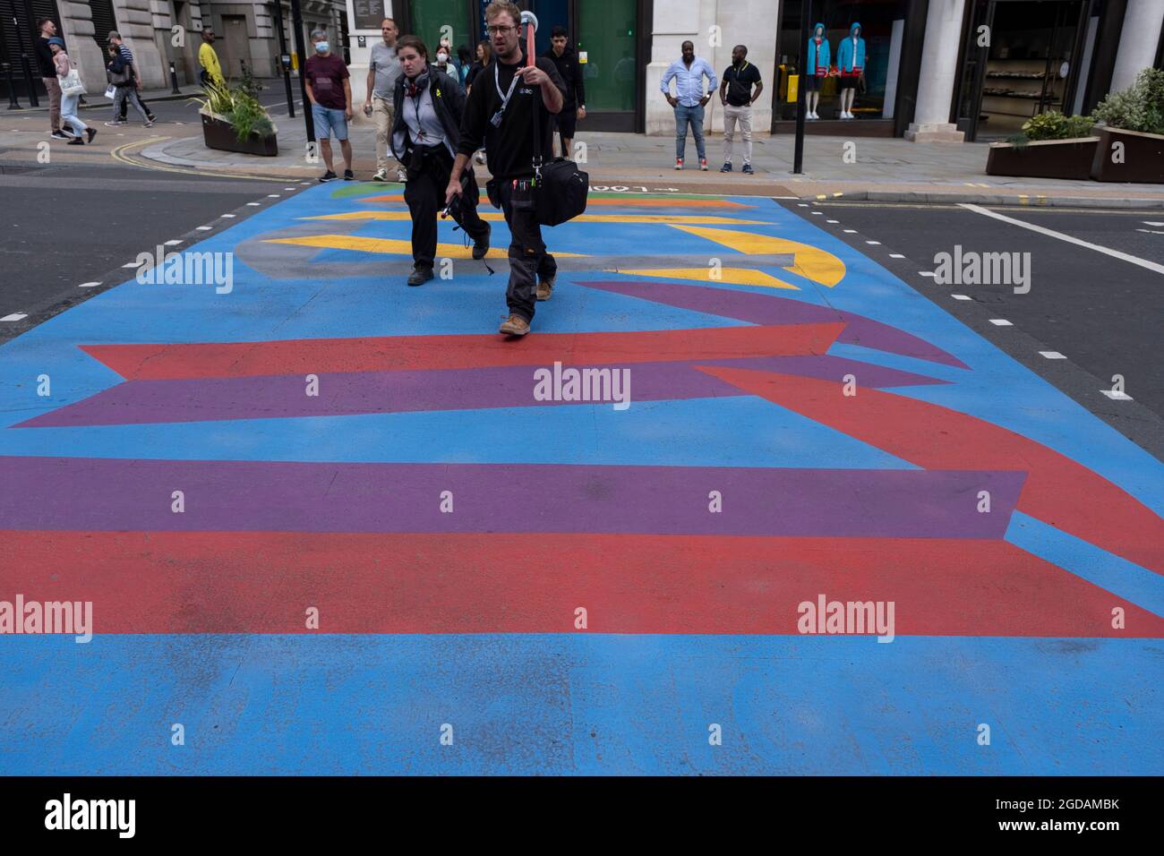 Da viele Menschen und Familien während der Schulferien in Großbritannien ihren Sommerurlaub verbringen, ist eine große Anzahl von Inlandstouristen, Wer normalerweise ins Ausland gereist ist, hat sich in der Hauptstadt decendiert, um die Sehenswürdigkeiten zu sehen, wie man hier im Piccadilly Circus sieht, als die Menschen am 10. August 2021 in London, Großbritannien, die neuen grafischen und gemusterten mehrfarbigen Fußgängerübergänge überqueren. Nach dem Coronavirus/Covid-19-Gesundheitssorge der letzten zwei Jahre und mit einigen Reisebeschränkungen, die noch bestehen, haben sich mehr Menschen für einen Aufenthalt entschieden, der ein Urlaub in ihrem Heimatland ist Stockfoto