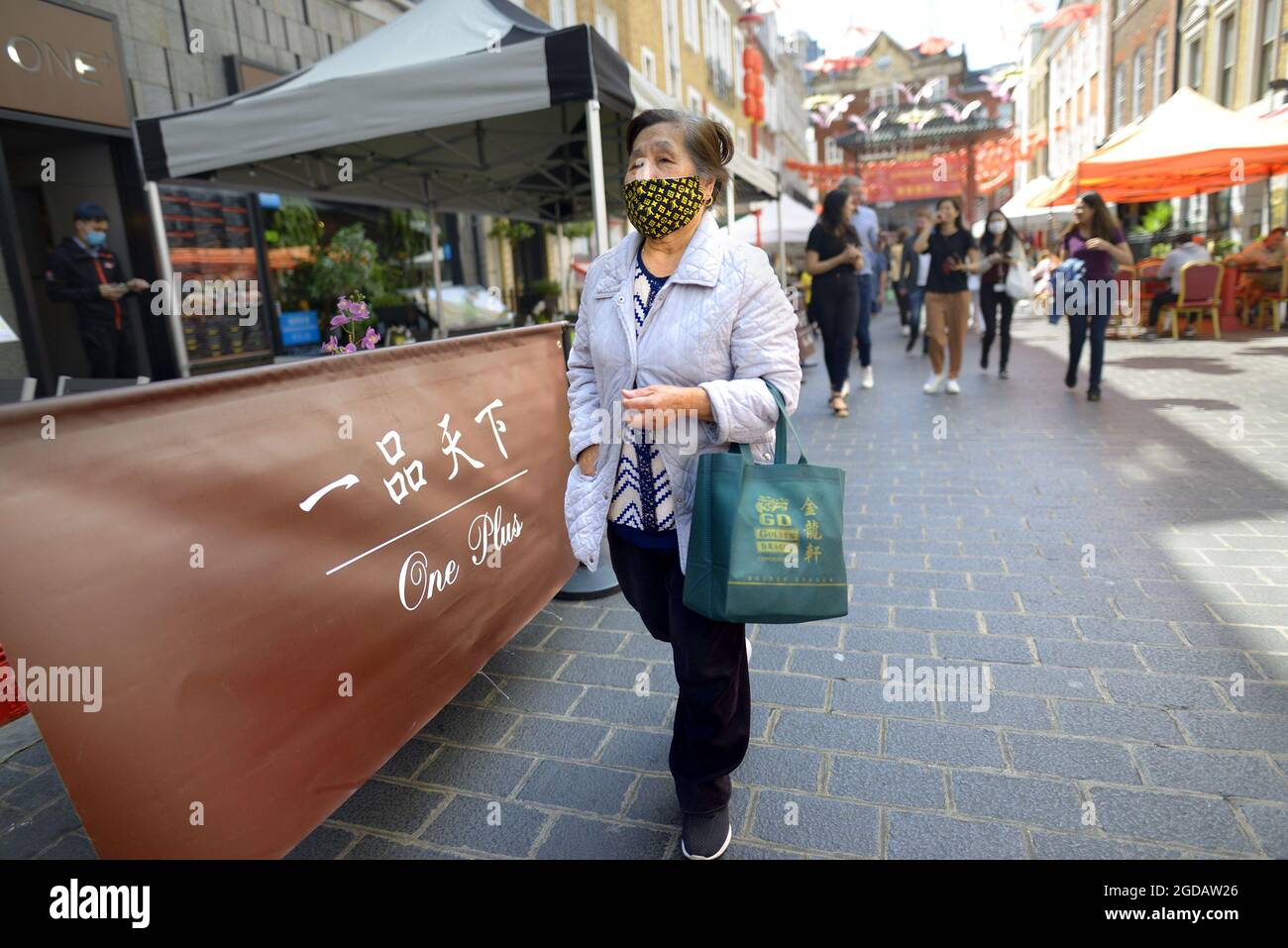 London, England, Großbritannien. Ältere Dame in der Gerrard Street, Chinatown, die während des COVID, Juli 2021, eine Gesichtsmask trug Stockfoto