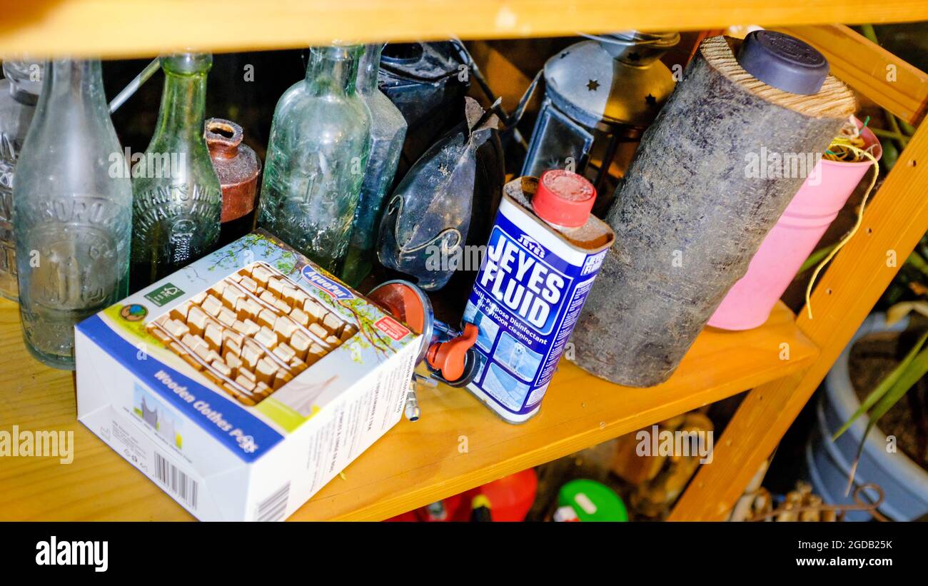 Ein Regal im Schuppen gefüllt mit Gartengeräten und Flaschen Stockfoto