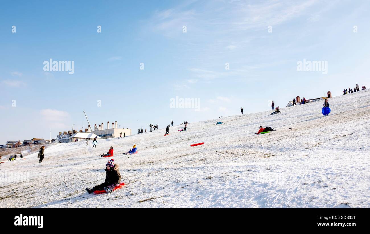 Familien, die im Winter auf den Tankerton Pisten, Kent, Großbritannien, Spaß beim Rodeln im Schnee haben Stockfoto