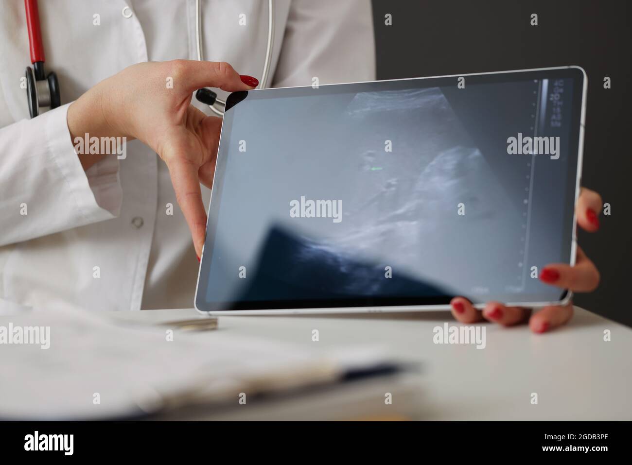 Arzt, der in der Nahaufnahme der Klinik eine Ultraschalluntersuchung des Abdomens auf einer digitalen Tablette vorführt Stockfoto