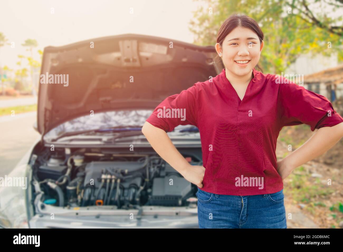 Portrait glückliche Frauen stehen vor zerbrochenen Unfällen Auto offene Haube lächelnd wartet Autoversicherung am Straßenrand ohne Sorge. Stockfoto