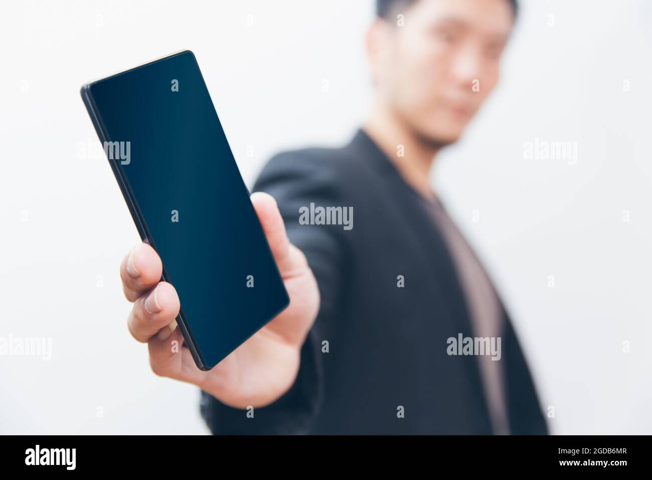 Geschäftsmann verteilt eine Handyshow leer Bildschirm mit weißem Hintergrund geringe Schärfentiefe. Stockfoto