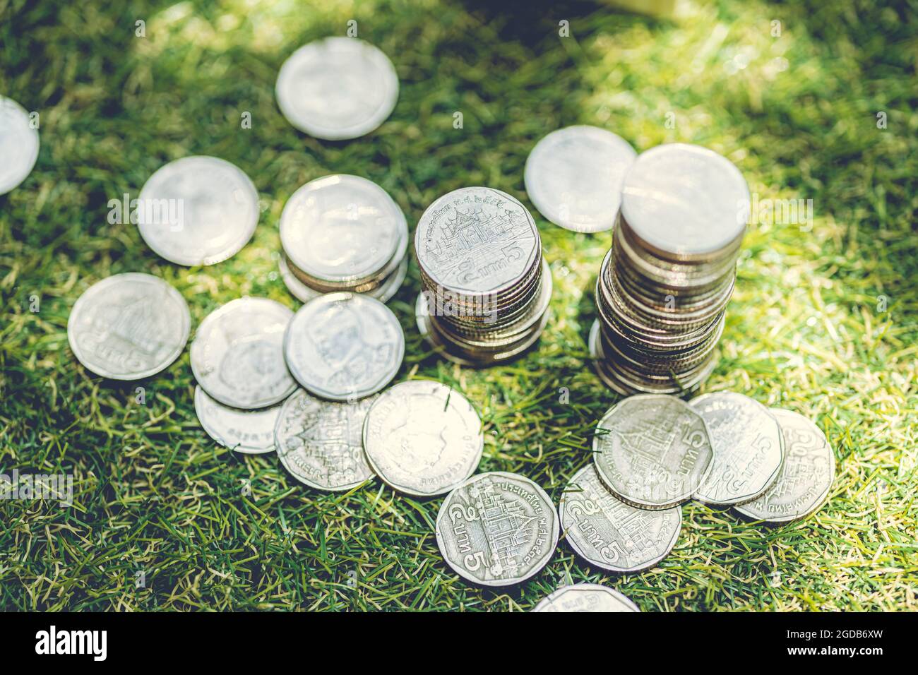 Stapel von Münzen Geld Thai Bad auf dem Boden Gras Natur Hintergrund mit Morgensonne scheinen platziert. Stockfoto