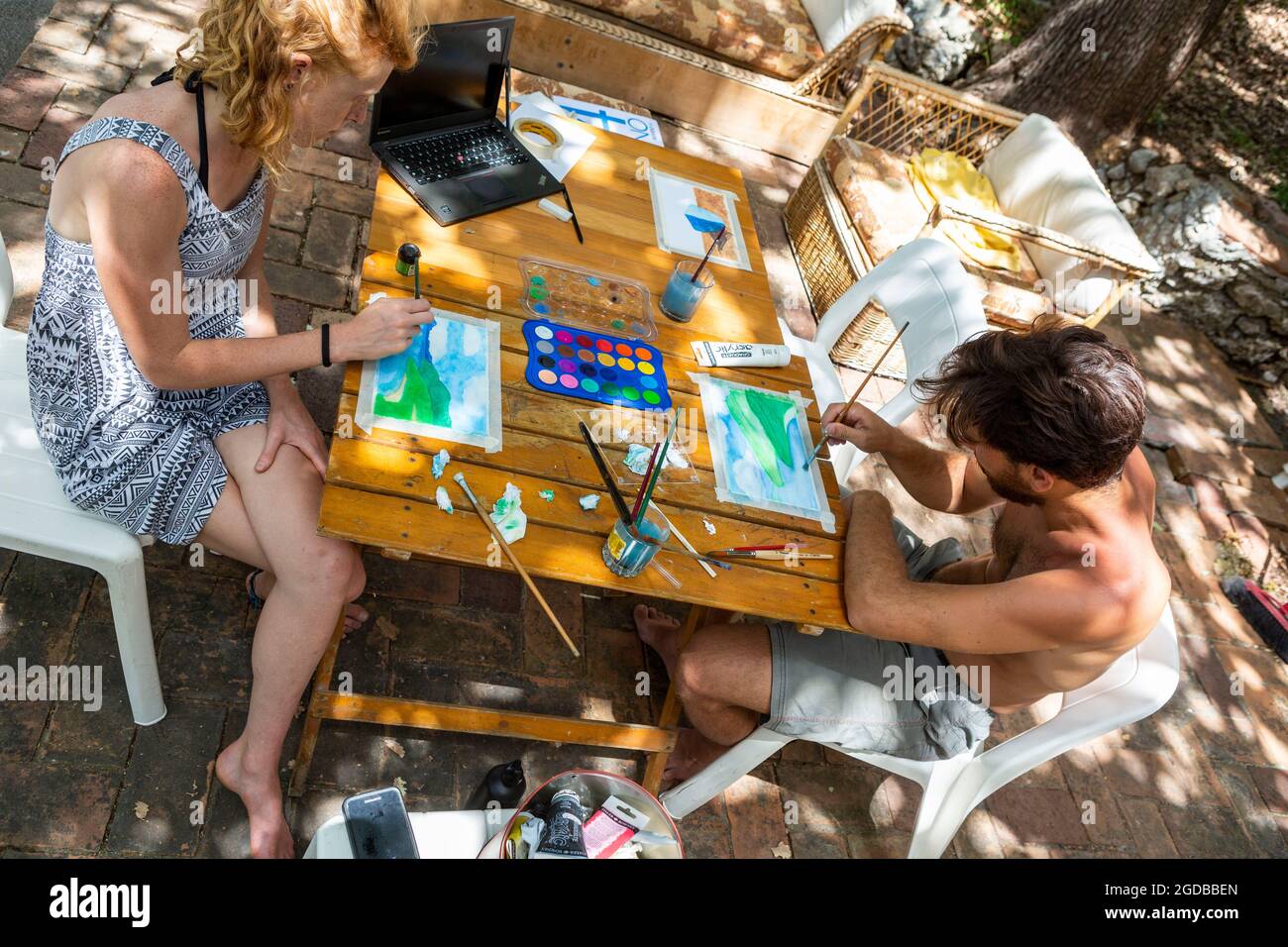 Junges Paar in den Zwanzigern, das mit Wasserfarben an einem Tisch im Freien malte Stockfoto