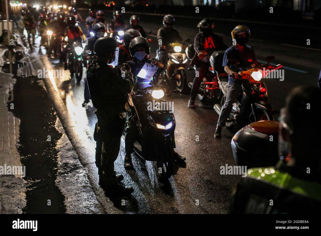 Polizisten mit Schutzausrüstung inspizieren Motorradfahrer an einem Kontrollpunkt während einer strengeren Sperre als Vorsichtsmaßnahme gegen die Ausbreitung der neuen Coronavirus-Krankheit am Stadtrand von Marikina City, Philippinen. Stockfoto