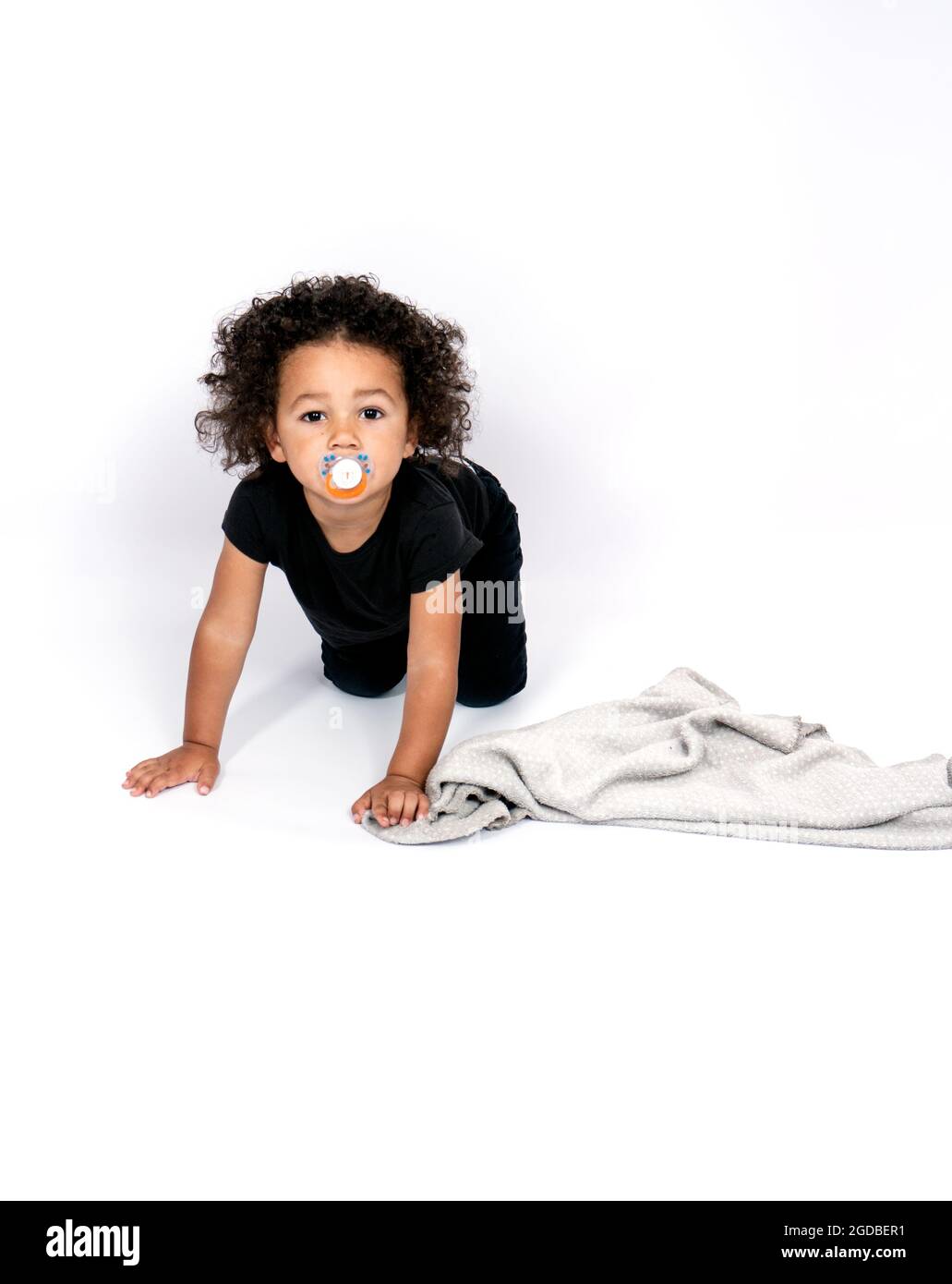Vertikales Porträt einer gemischten Rasse, 2 Jahre und halb alter Junge, der beim Krabbeln einen Nippel saugt Stockfoto