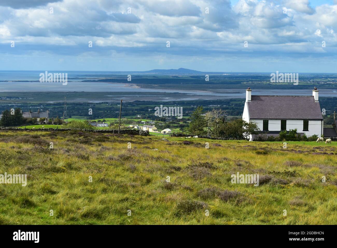 Landschaft in Snowdonia, Nordwales. Wolken und Himmel. Kleines Häuschen auf einem windgepeitschten Hügel mit Blick über das Meer auf die wunderschöne walisische Insel Ang Stockfoto