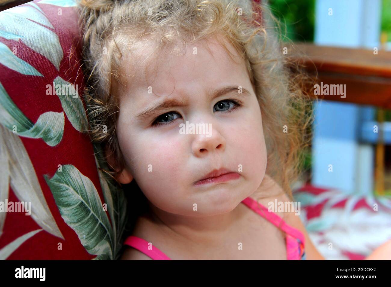 Das kleine Mädchen hat ihr Gesicht in einem Grind verdreht. Ihre Einstellung ist mürrisch und pingelig. Sie hat lockiges Haar. Stockfoto
