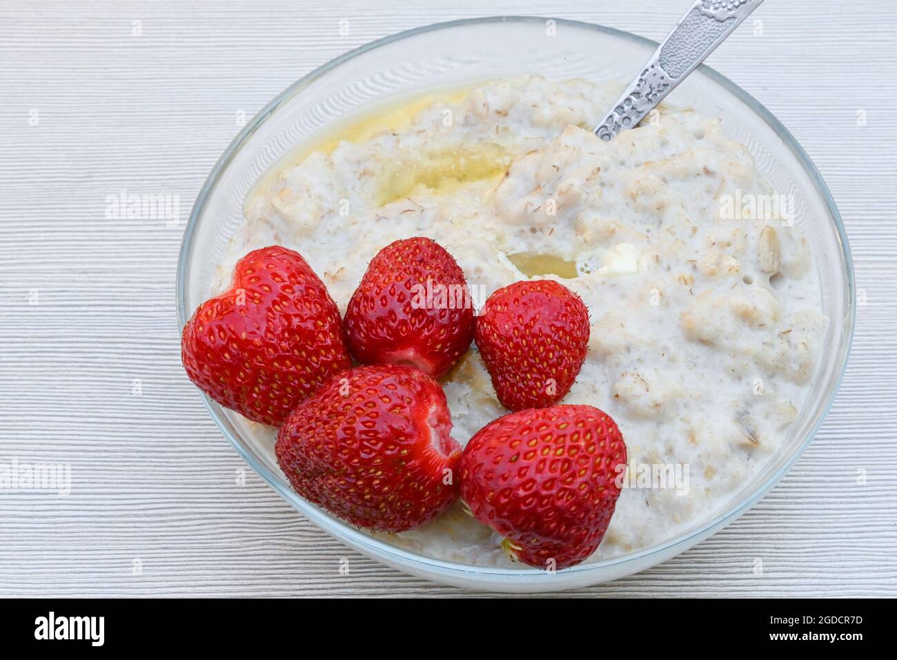 Ein Teller mit Haferbrei und reifen saftigen Erdbeeren auf einem weißen Tisch Stockfoto