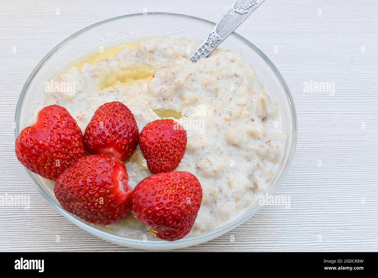 Ein Teller mit Haferbrei und reifen saftigen Erdbeeren auf einem weißen Tisch Stockfoto