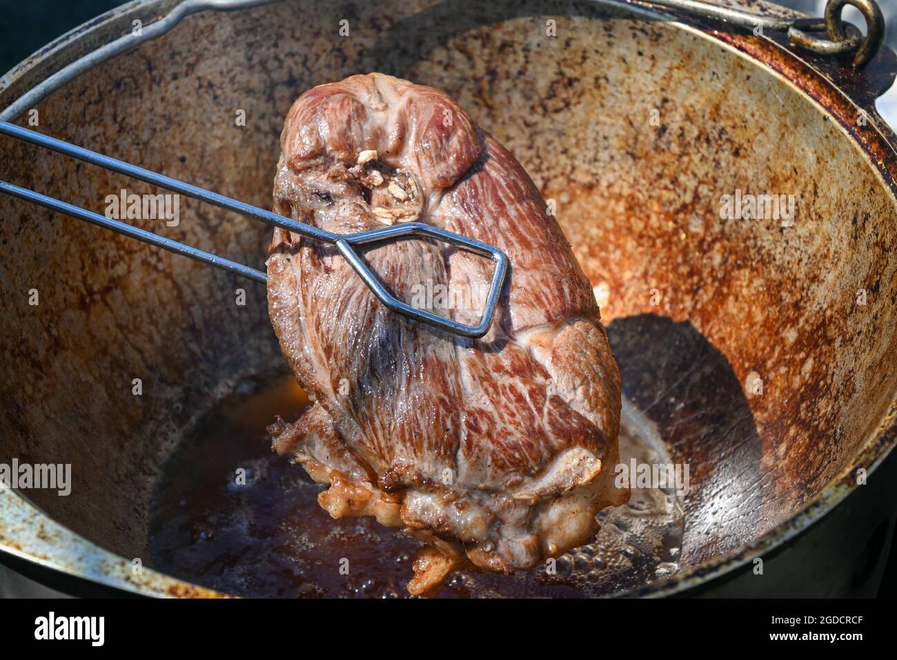 Ein Stück Fleisch wird in kochendem Öl gebraten. Kochen von Pilaf in einem Kessel, ein Schritt-für-Schritt-Rezept für echten Pilaf. Stockfoto