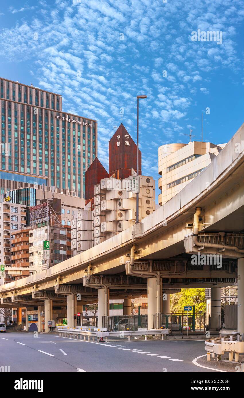 tokio, japan - 05 2021. juli: Shuto Expressway im Shimbashi-Viertel mit dem ikonischen Gebäude des Nakagin Capsule Tower, das von einer verrosteten Dachgittern gekrönt wird Stockfoto
