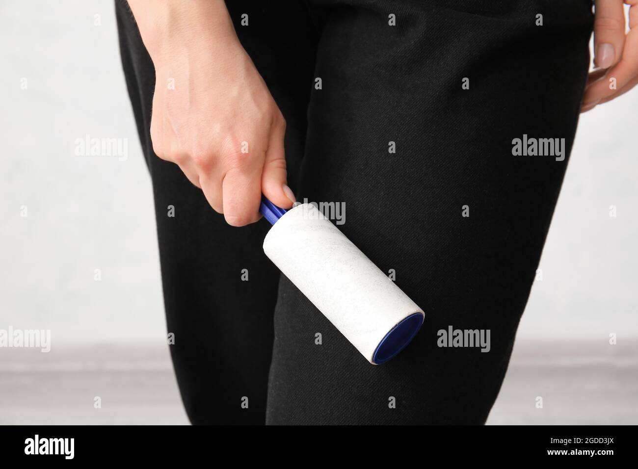 Frau Reinigung Kleidung mit Kleiderrolle oder Flusenrolle von Katzen Haar. Die Katze wirft sich. Tierhaare auf der Kleidung. Reinigung von Haaren von Haustieren Stockfotografie