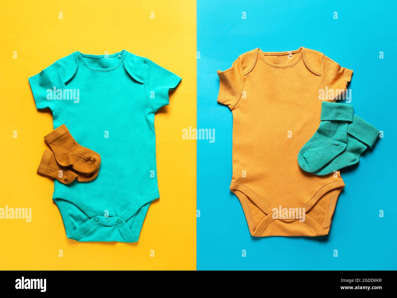 Baby-Bodys und -Socken auf farbigem Hintergrund Stockfoto