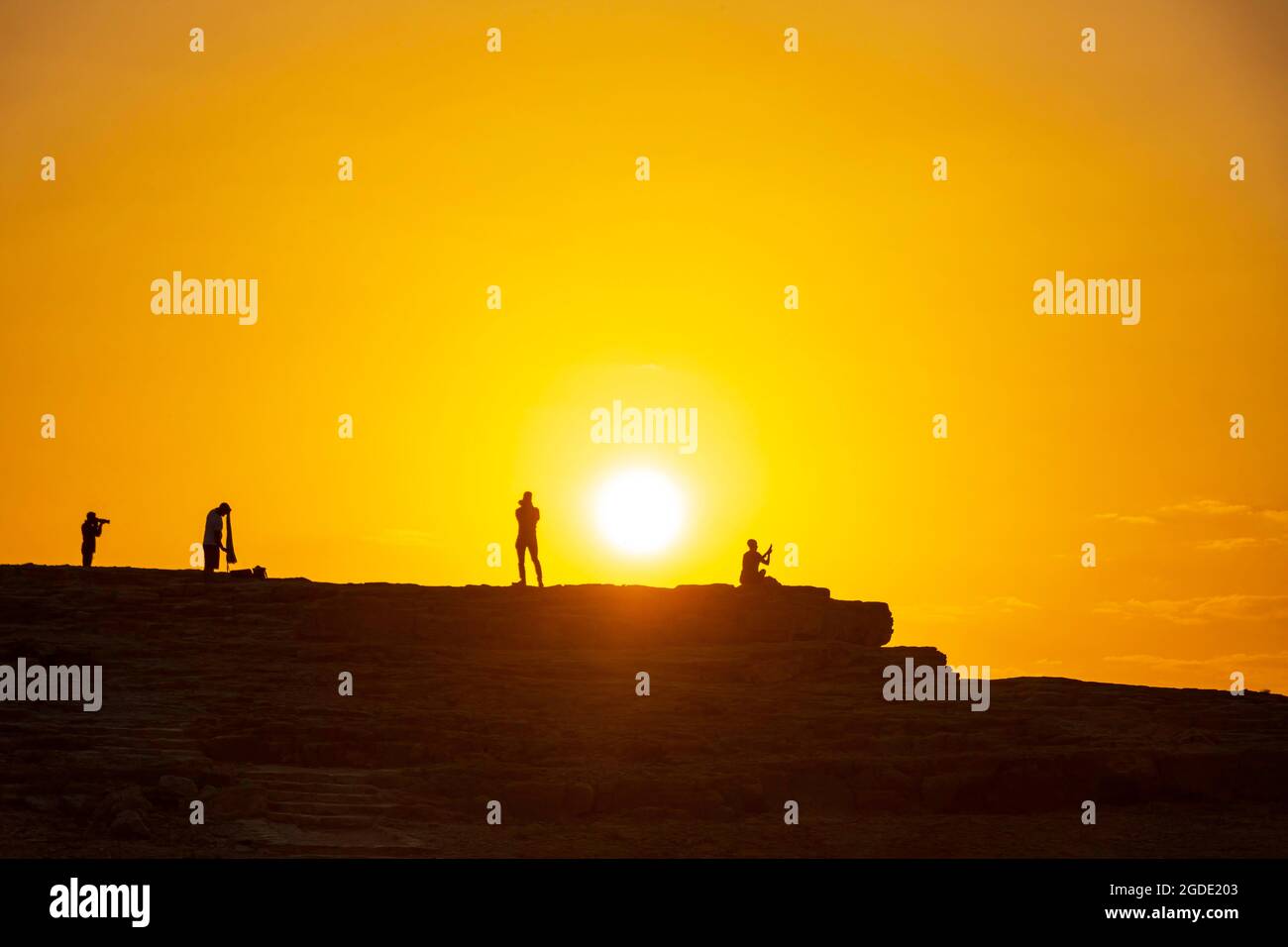 Silhouetten von Fotografen vor dem Hintergrund der aufgehenden Sonne. Makhesh Ramon Stockfoto