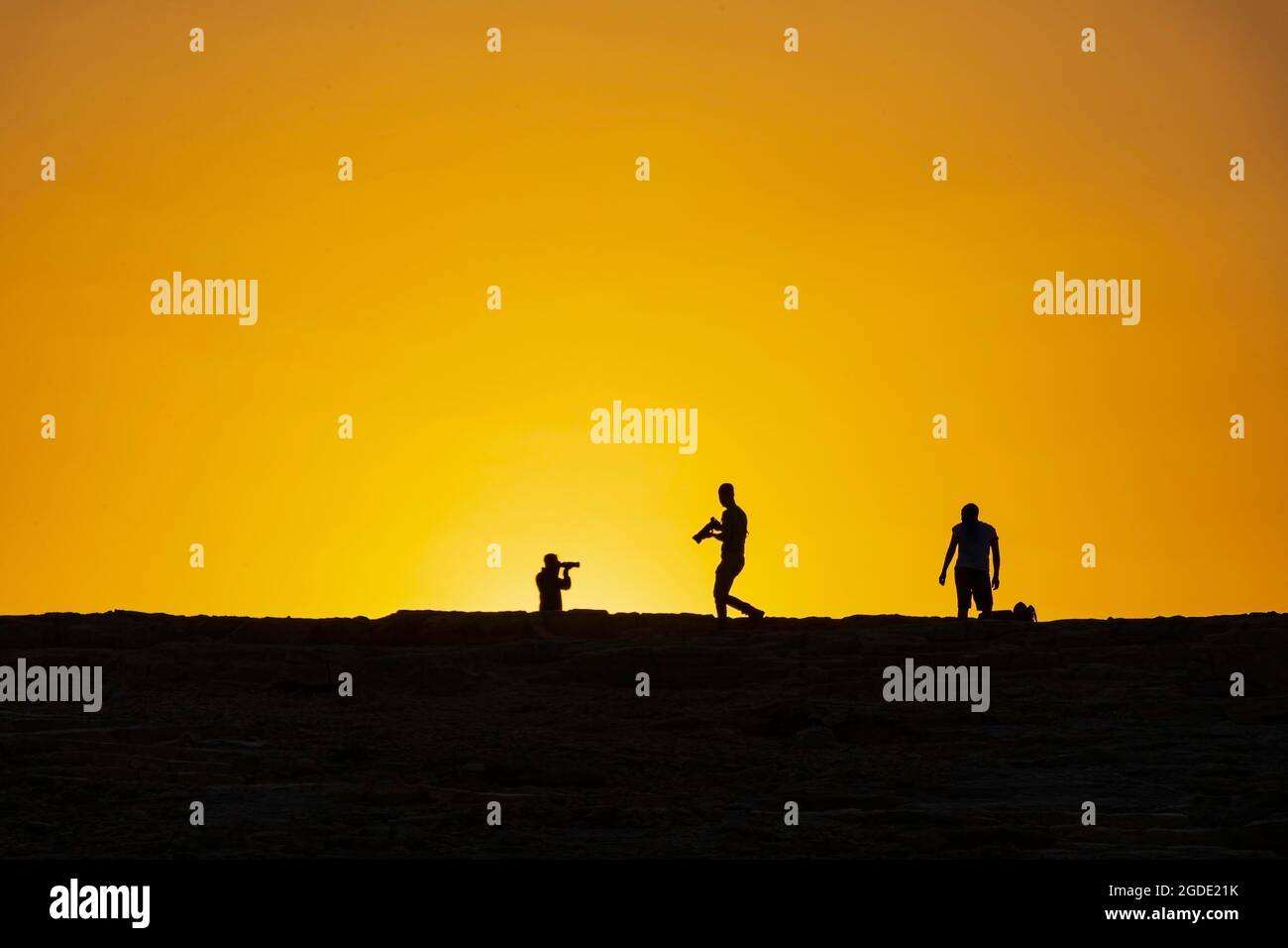 Silhouetten von Fotografen vor dem Hintergrund der aufgehenden Sonne. Makhesh Ramon Stockfoto