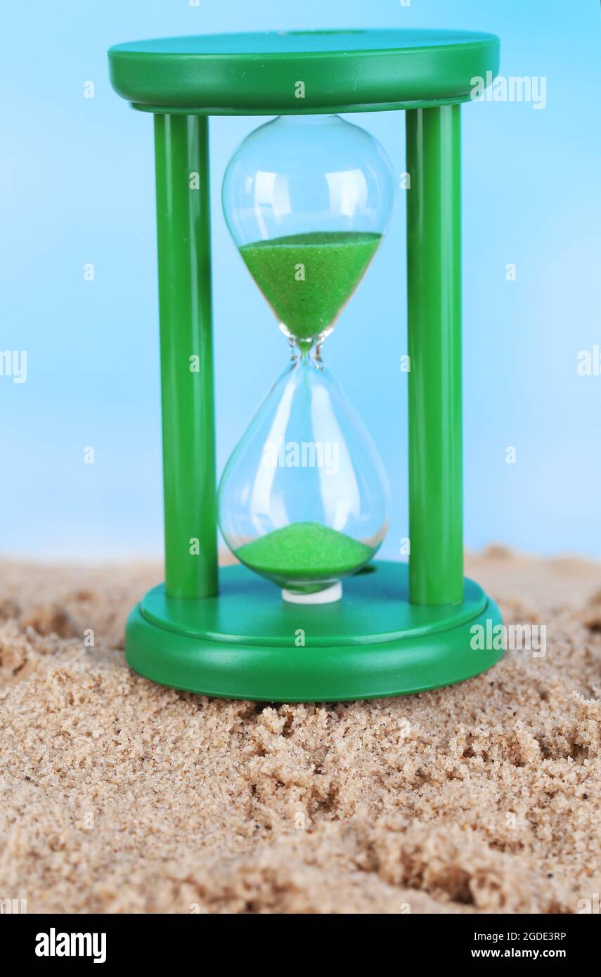Sanduhr in Sand auf blauem Himmel Hintergrund Stockfotografie - Alamy