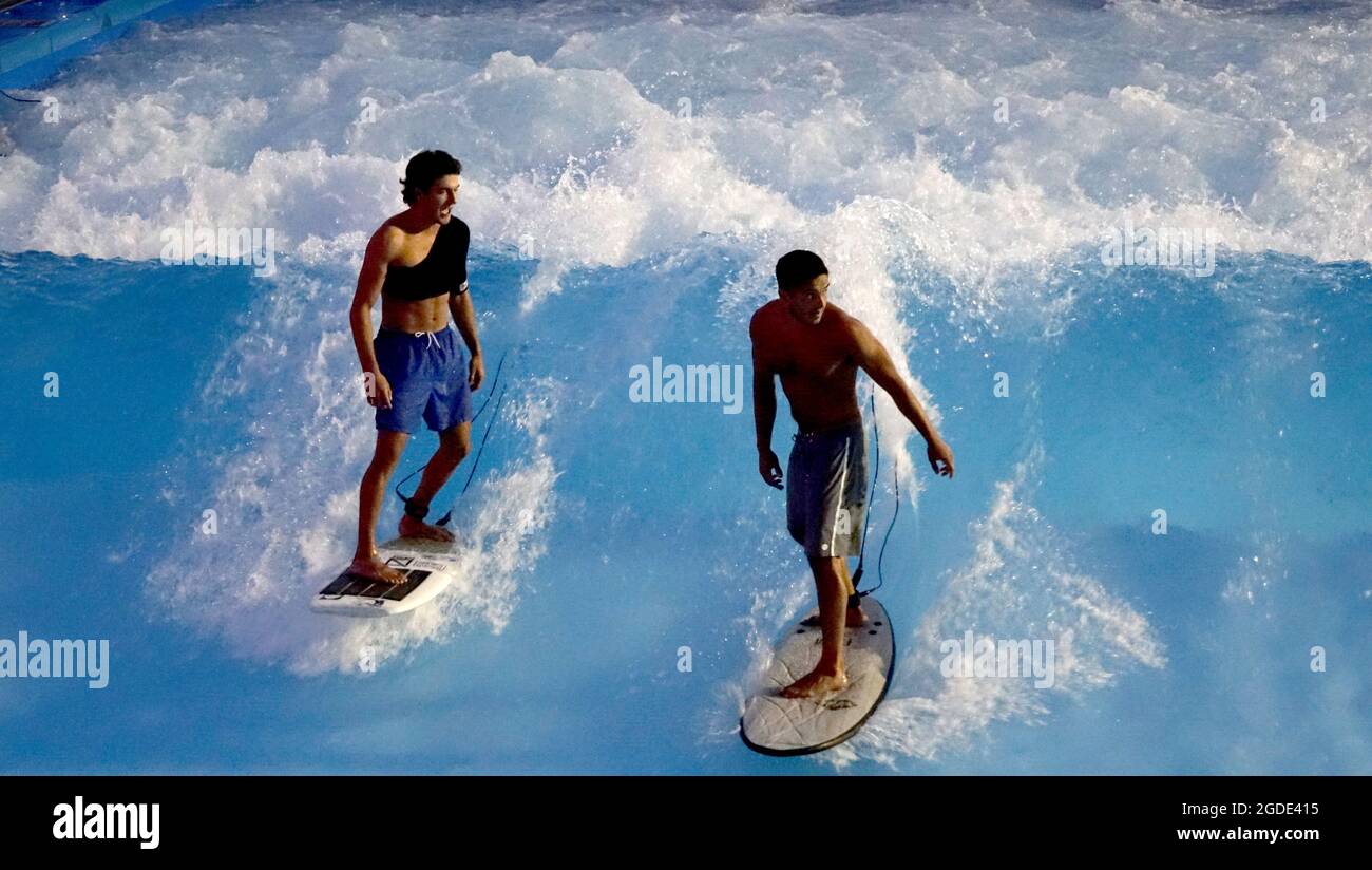 Lakeside Surf, gebaut von der German City Wave Company, ist die größte stationäre Surfwelle. Ein neuer Surfer bekommt Wellenunterricht von einem Lakeside Sur Stockfoto