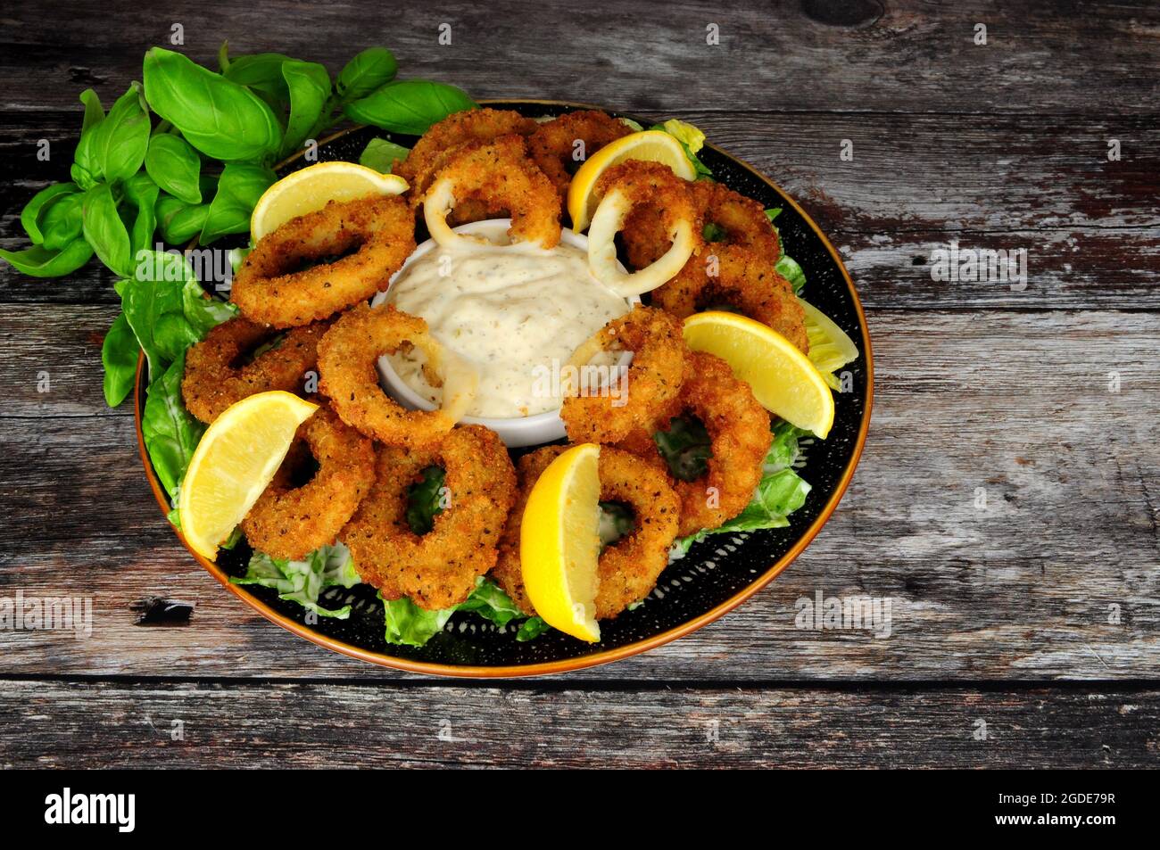Mit Breadcrumb überzogene Calamari-Tintenfischringe mit Salz und Pfeffer, einer Tartar-Dipping-Sauce und frischen Zitronen Stockfoto