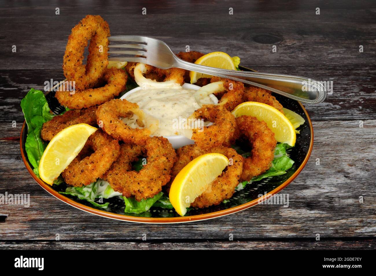 Mit Breadcrumb überzogene Calamari-Tintenfischringe mit Salz und Pfeffer, einer Tartar-Dipping-Sauce und frischen Zitronen Stockfoto