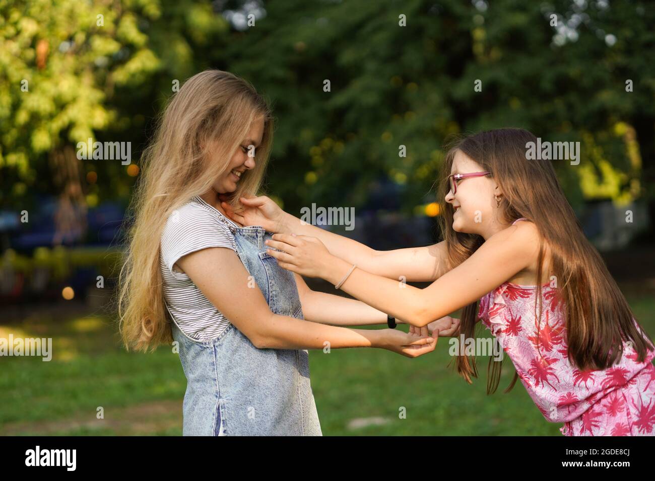 Das kleine Mädchen umarmt ihre ältere Schwester. Liebe und Freundschaft. Glückliches Familienkonzept. Stockfoto