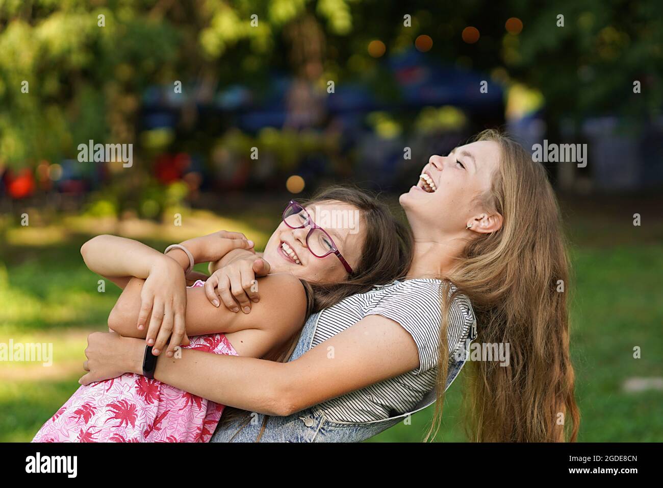 Schöne junge Frau umarmt ihre jüngere Schwester. Liebe und Freundschaft. Glückliches Familienkonzept. Stockfoto