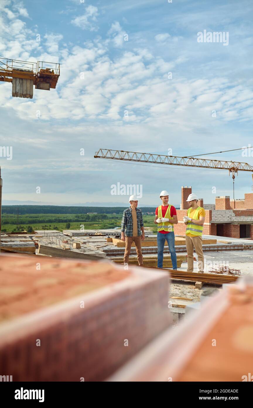 Drei Männer in Schutzhelmen stehen auf der Baustelle Stockfoto