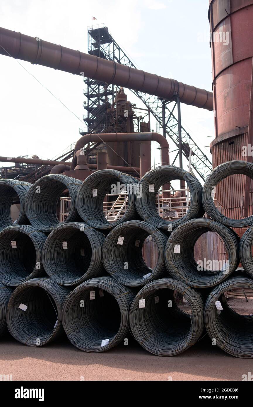 Hamburg, Deutschland. August 2021. Ein Hochofen hinter gestapelten Drahtwicklungen auf dem Gelände eines Stahlwerks der Firma ArcelorMittal GmbH. Quelle: Jonas Walzberg/dpa/Alamy Live News Stockfoto