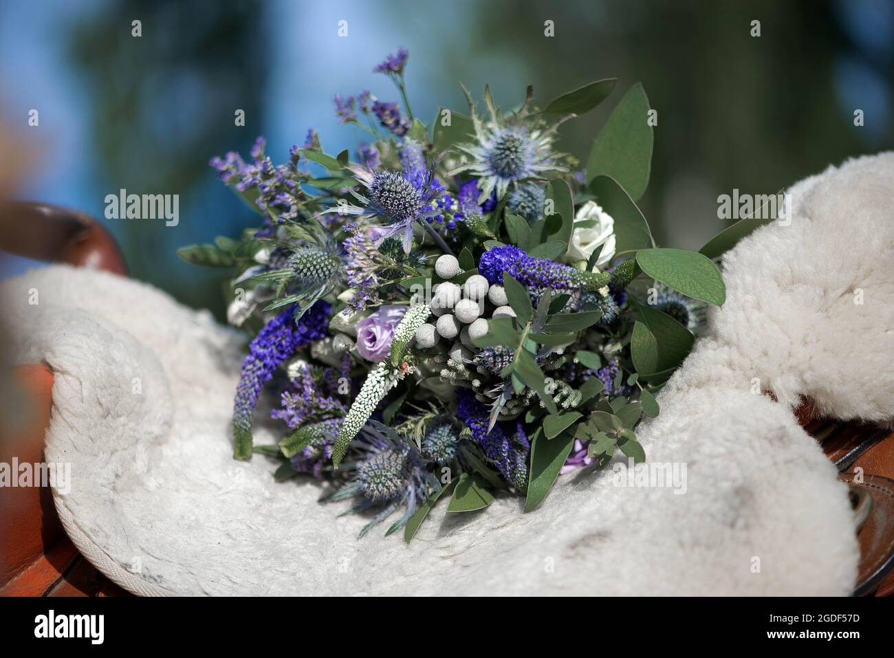 brautstrauß mit weißen, grünen und blauen Blumen auf dem Sattel eines Pferdes Stockfoto