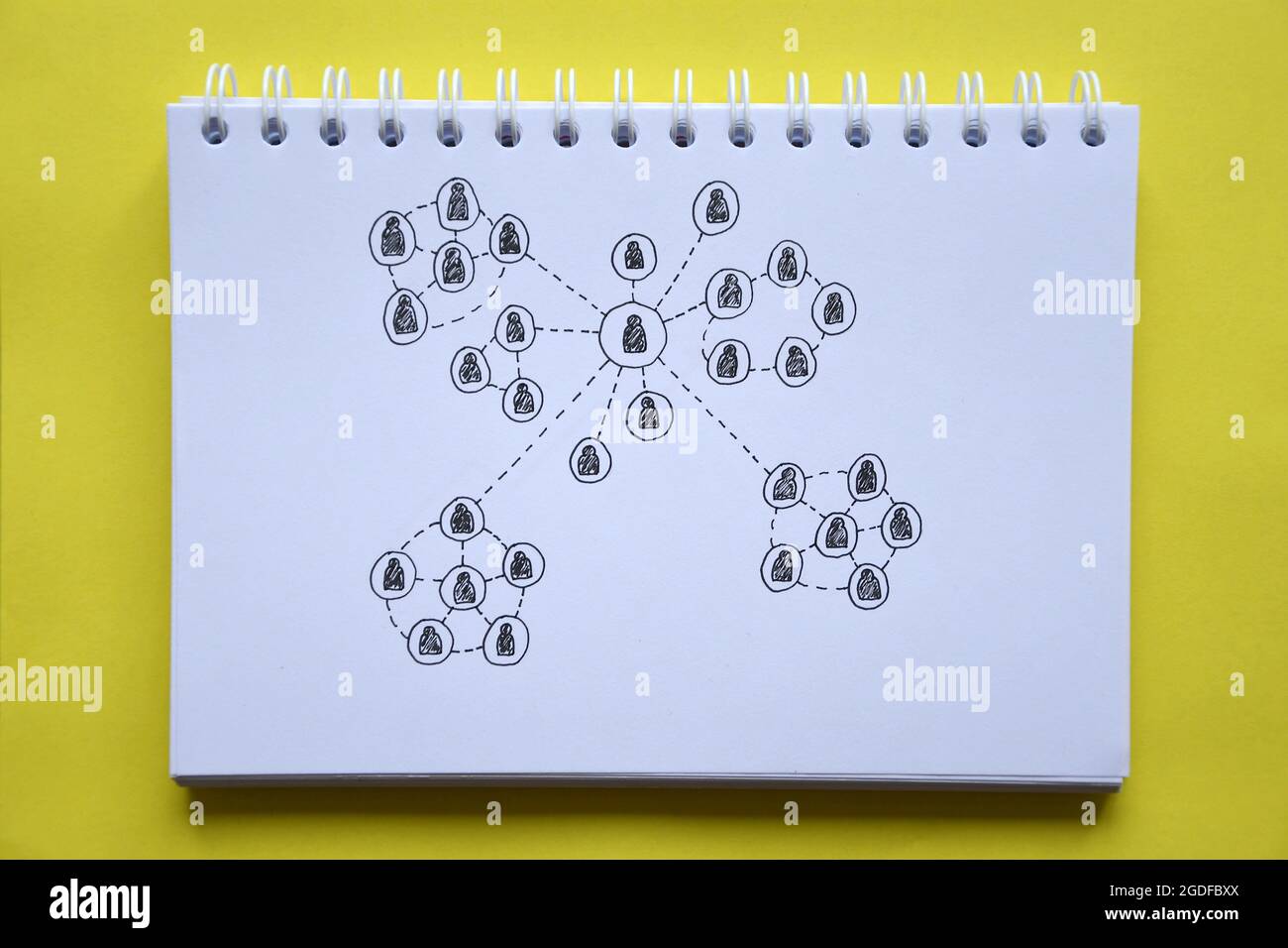 Overhead-Foto eines Notizbuchs mit einer Zeichnung eines sozialen Netzwerks auf gelbem Hintergrund Stockfoto