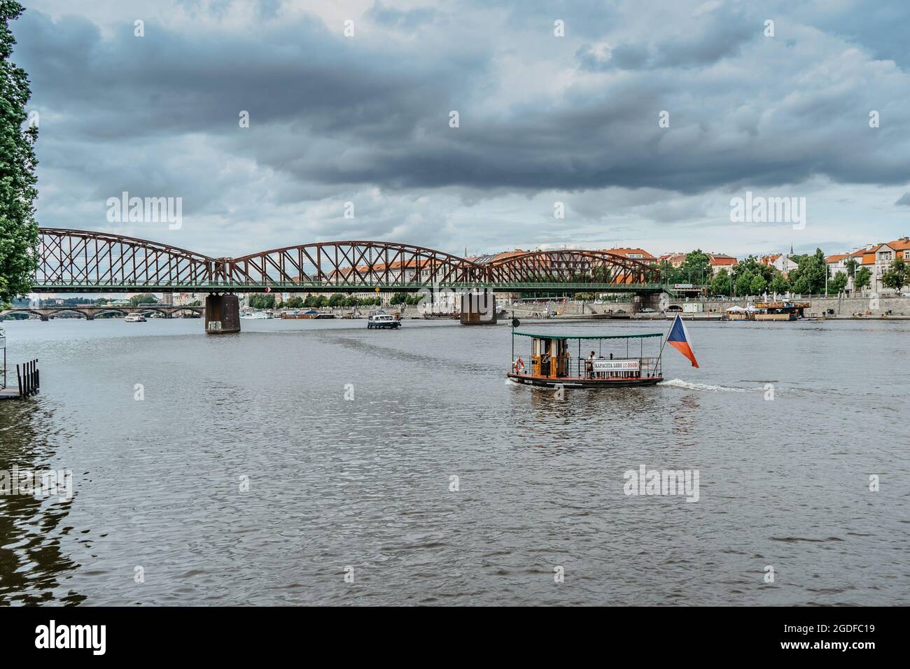 Prag, Tschechische Republik - August 4,2021. Kleine Holzfähre mit tschechischer Flagge und Passagiere, die die Moldau überqueren.Öffentliche Verkehrsmittel in der Stadt. Stockfoto