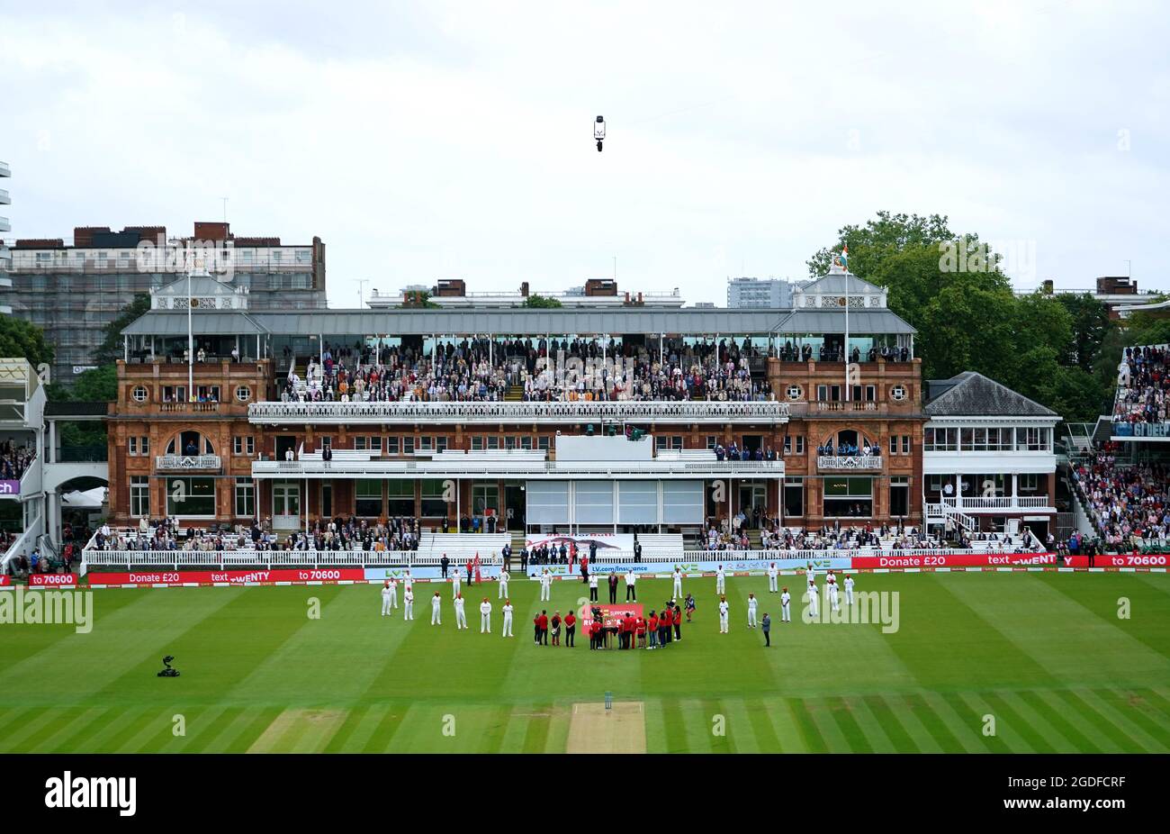 Die Spieler kreieren eine Herzform auf dem Spielfeld, während Sir Andrew Strauss, seine Kinder und andere Kinder, die von der Ruth Strauss Stiftung unterstützt wurden, vor dem zweiten Tag des Cinch Second Test Matches in Lord's, London, die Glocke läuten. Bilddatum: Freitag, 13. August 2021. Stockfoto