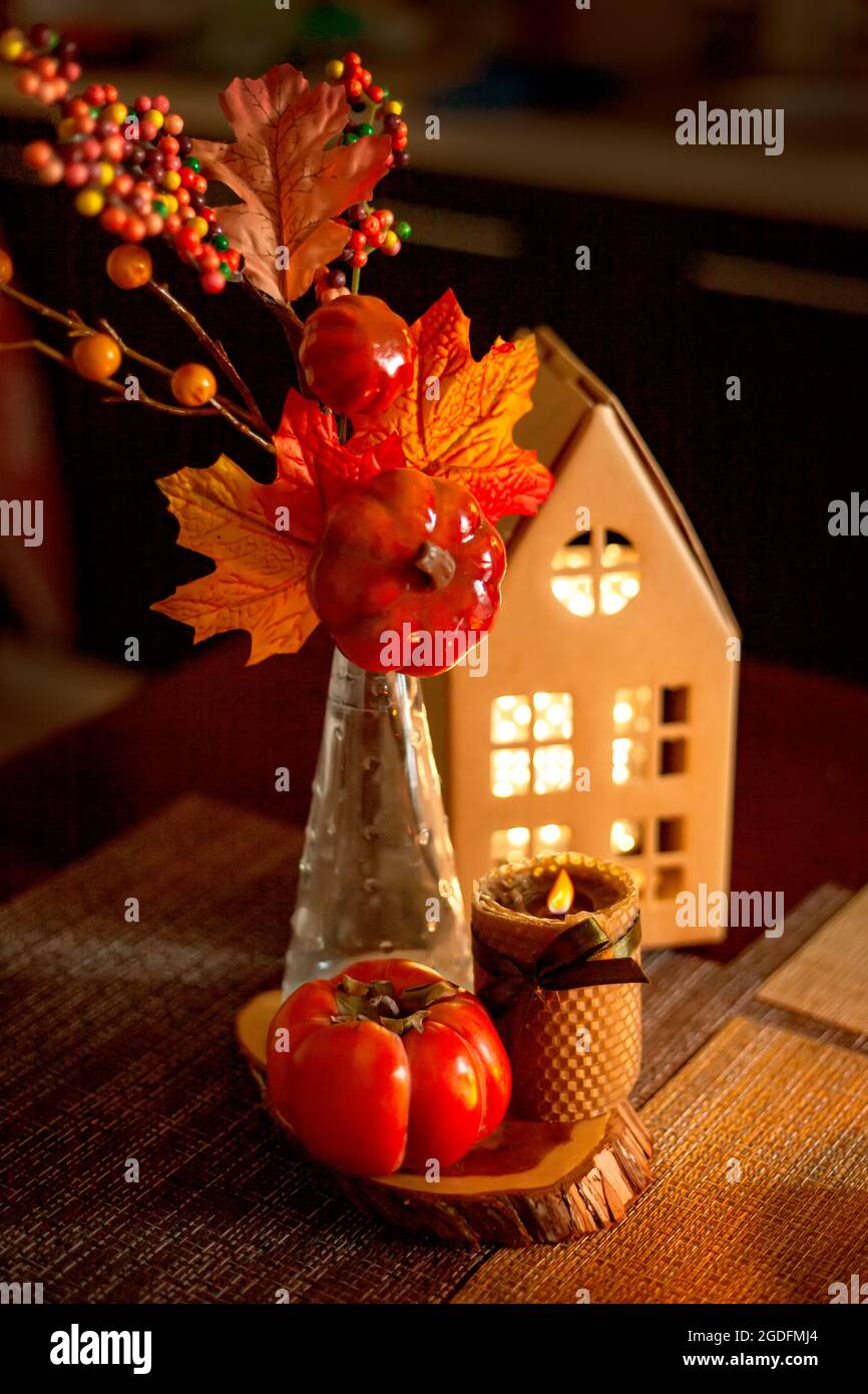 Küchendekoration für Halloween und Herbst - leuchtendes Papphaus, Kerze, Blumenstrauß mit Herbstblättern, Kakimmon Stockfoto