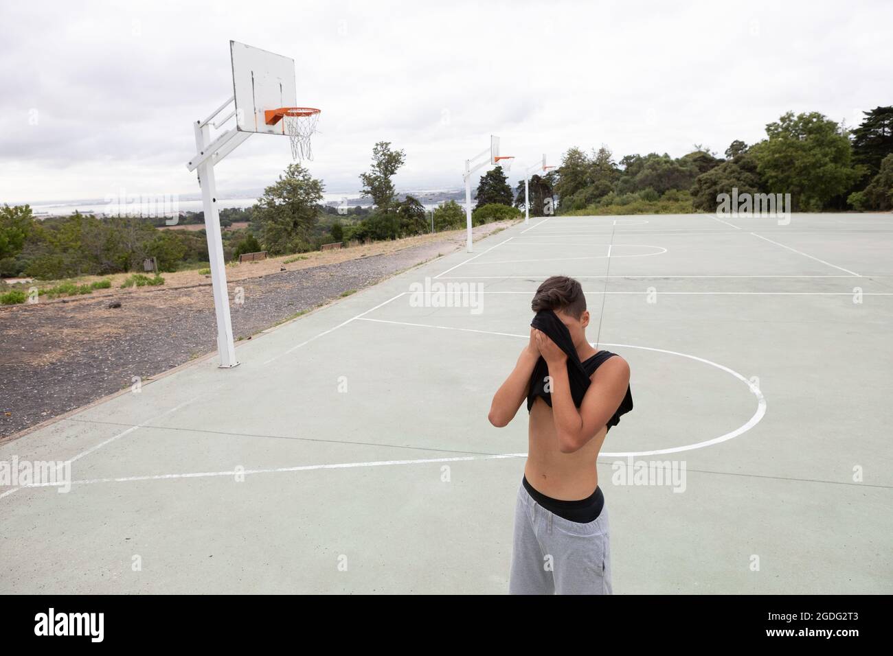 Männliche Teenager Basketball Spieler seine Stirn wischen mit Weste auf Basketball Court Stockfoto