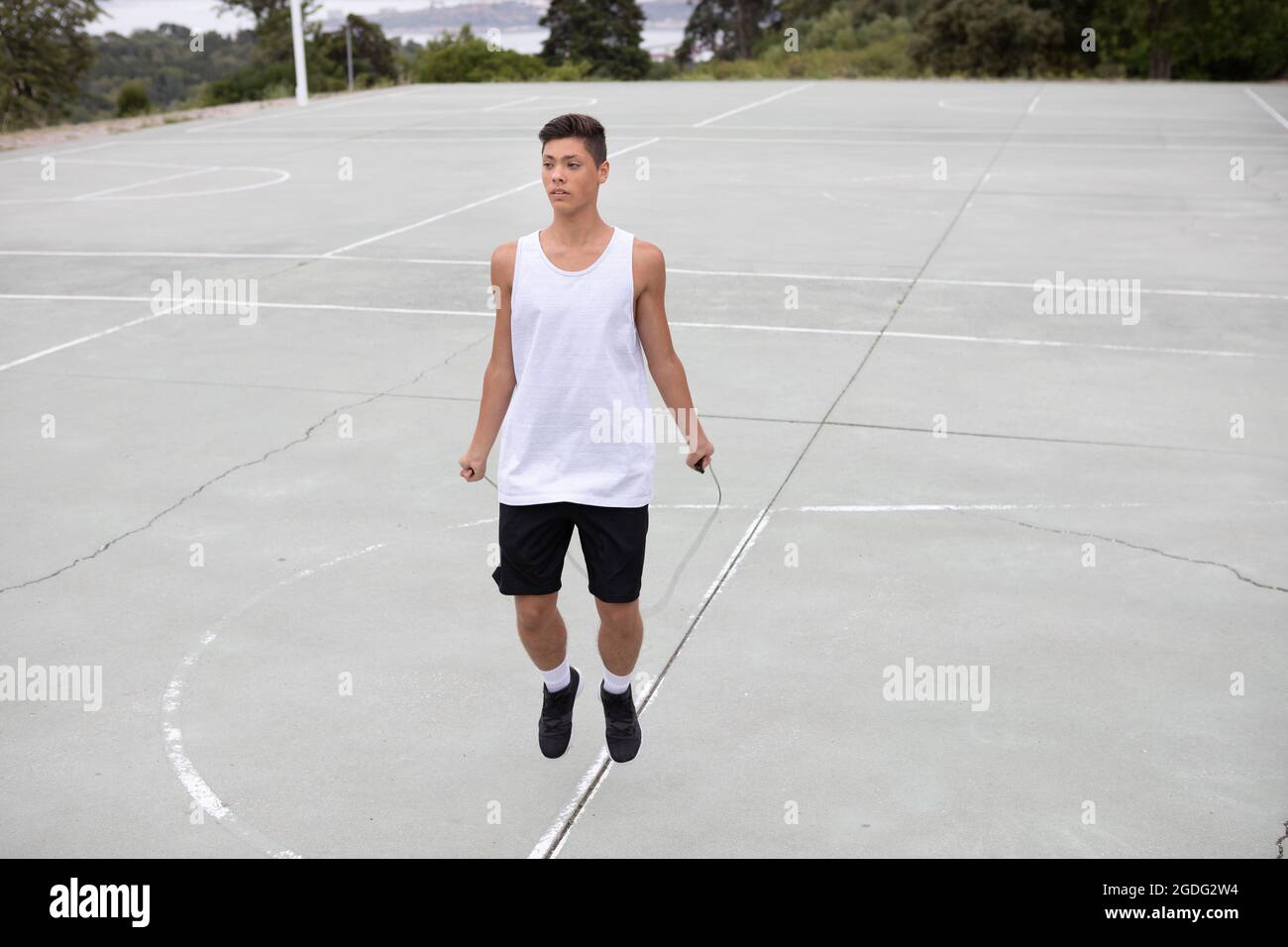 Männliche Teenager basketball Player auf Basketballplatz überspringen Stockfoto