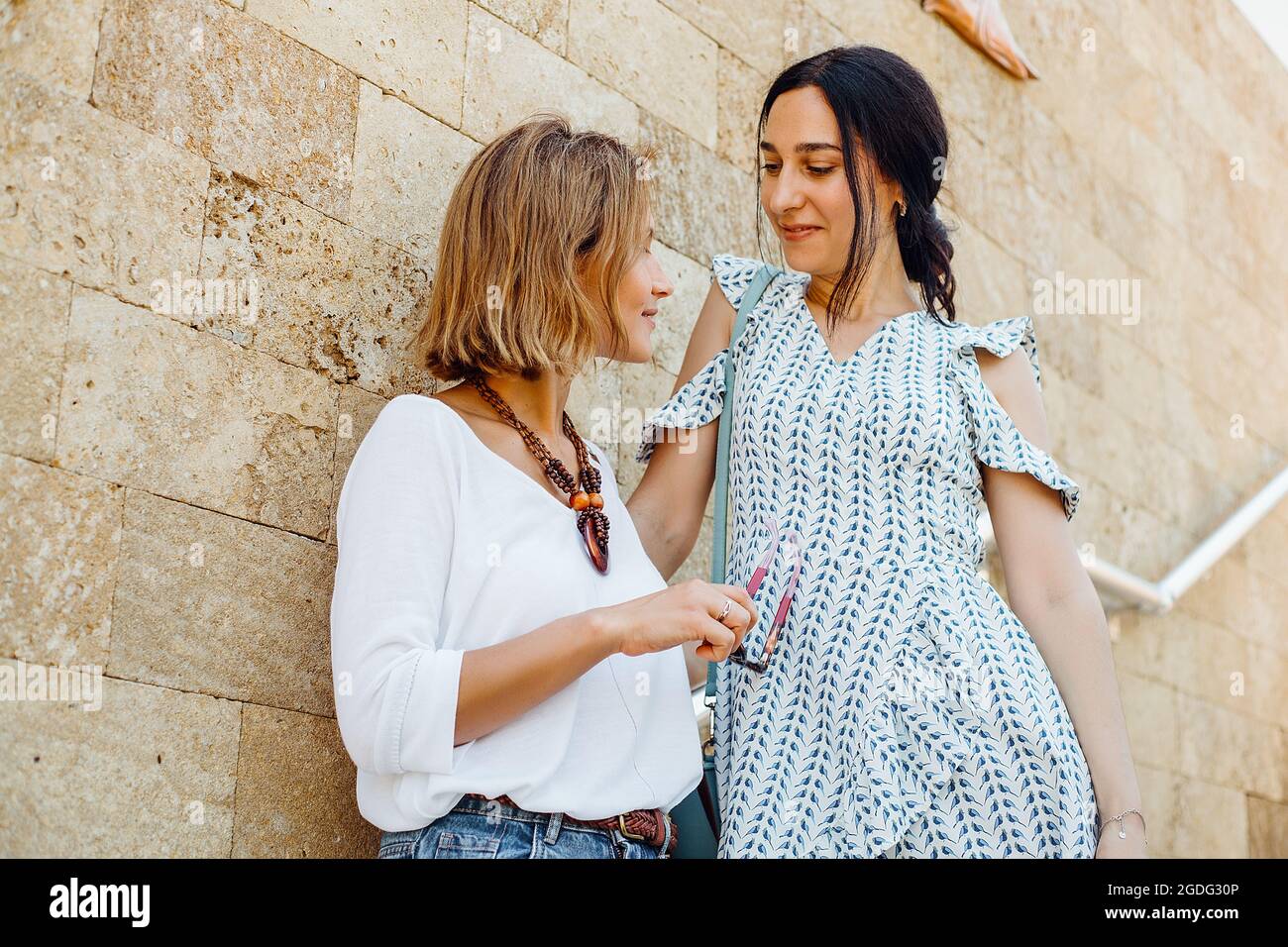 Freunde gegen stein Wand lehnt Stockfoto