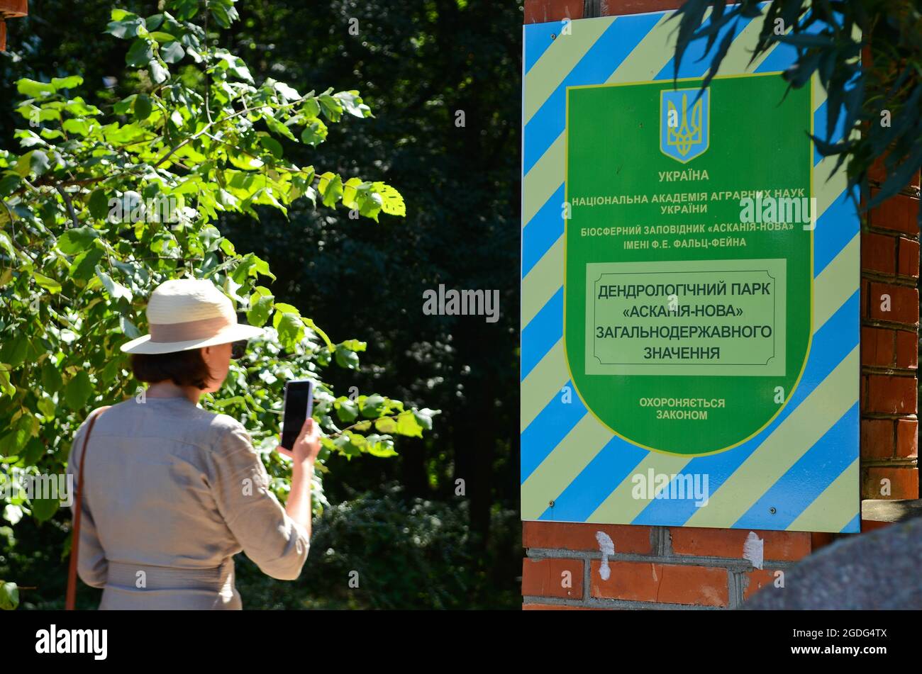 KHERSON REGION, UKRAINE - 1. AUGUST 2021 - EINE Frau fotografiert am Eingang des dendrologischen Parks des Friedrich-Jacob Falz-Fein Askania- Stockfoto