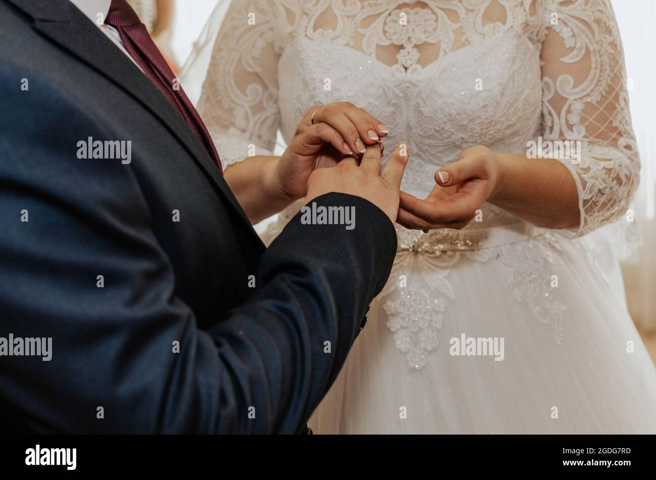 Die Braut und der Bräutigam tauschen die Ringe aus. Ein Mann legt einer  Frau einen Ehering an die Hand. Das Mädchen legte Ring auf den Mann.  Offizielle Hochzeitszeremonie im Register Stockfotografie -