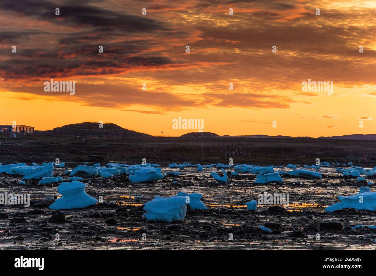 Atemberaubender Sonnenuntergang über der Küste, übersät mit schmelzenden Eisbergen. Stockfoto