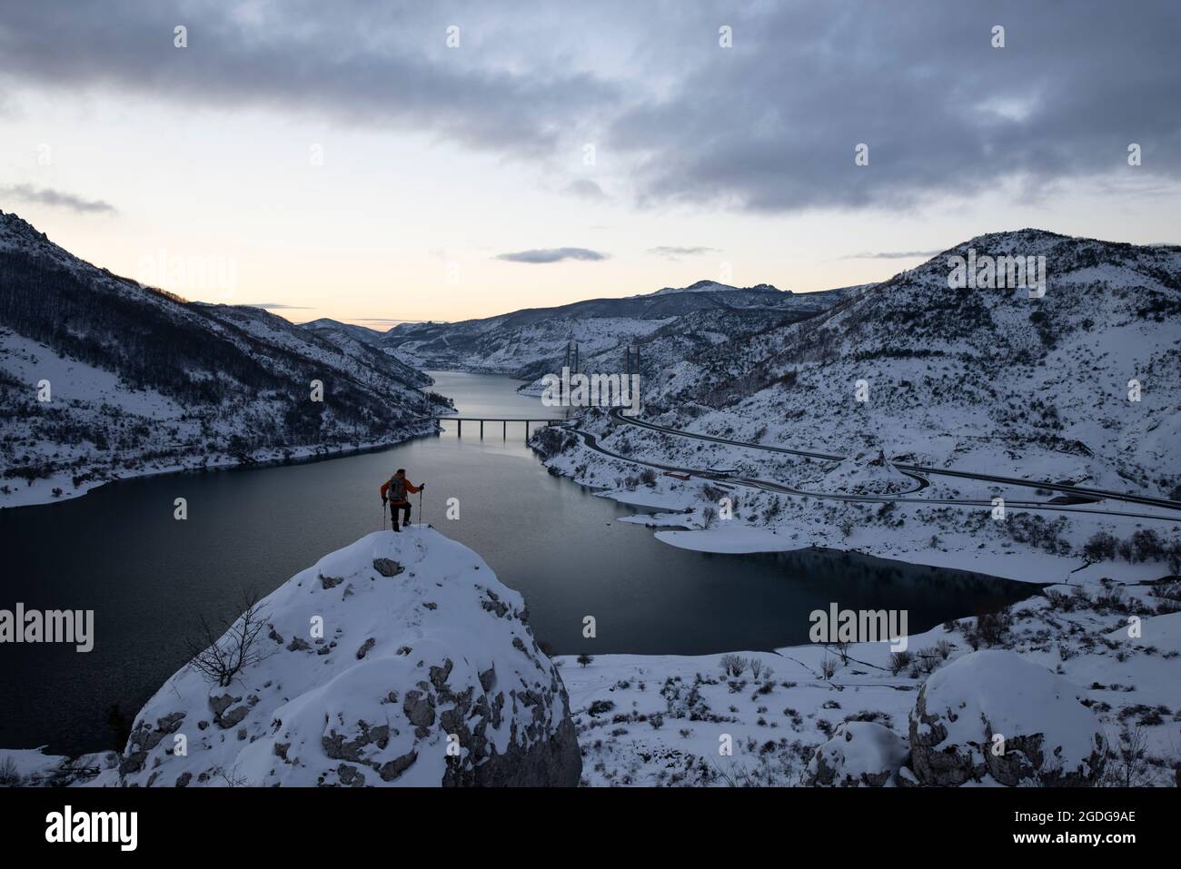 Bergsteiger beobachten den Stausee Barrios de Luna, der bei Sonnenaufgang schneit Stockfoto