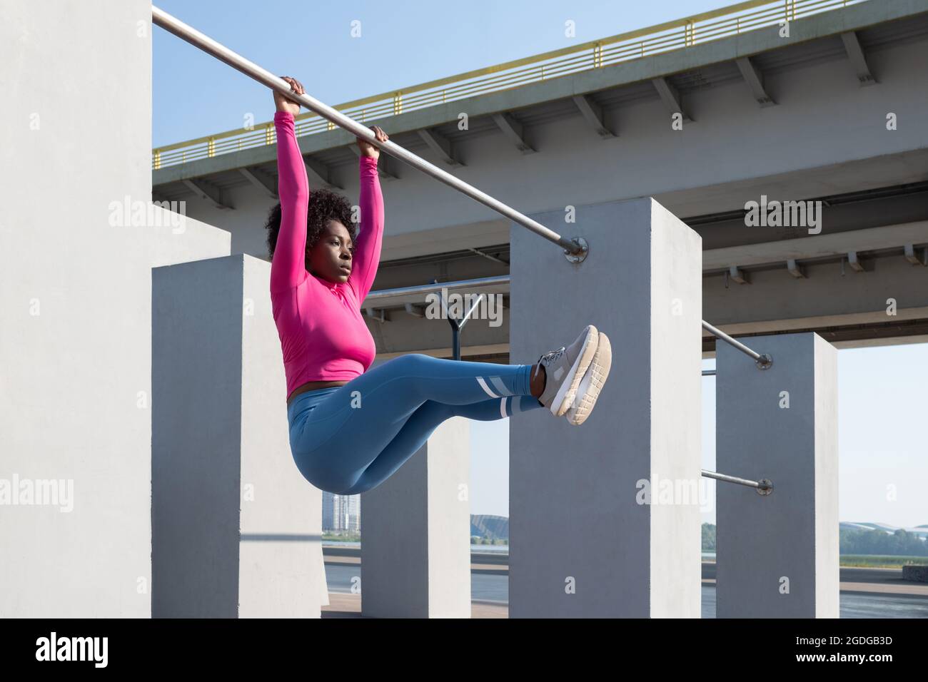 Schwarze Sportlerin hängt an der Pull-up-Stange und macht während des Trainings abs-Übungen Stockfoto