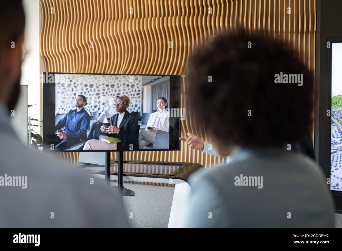Mitarbeiter, die während einer Videokonferenz mit verschiedenen Kollegen auf den Monitor schauen Stockfoto