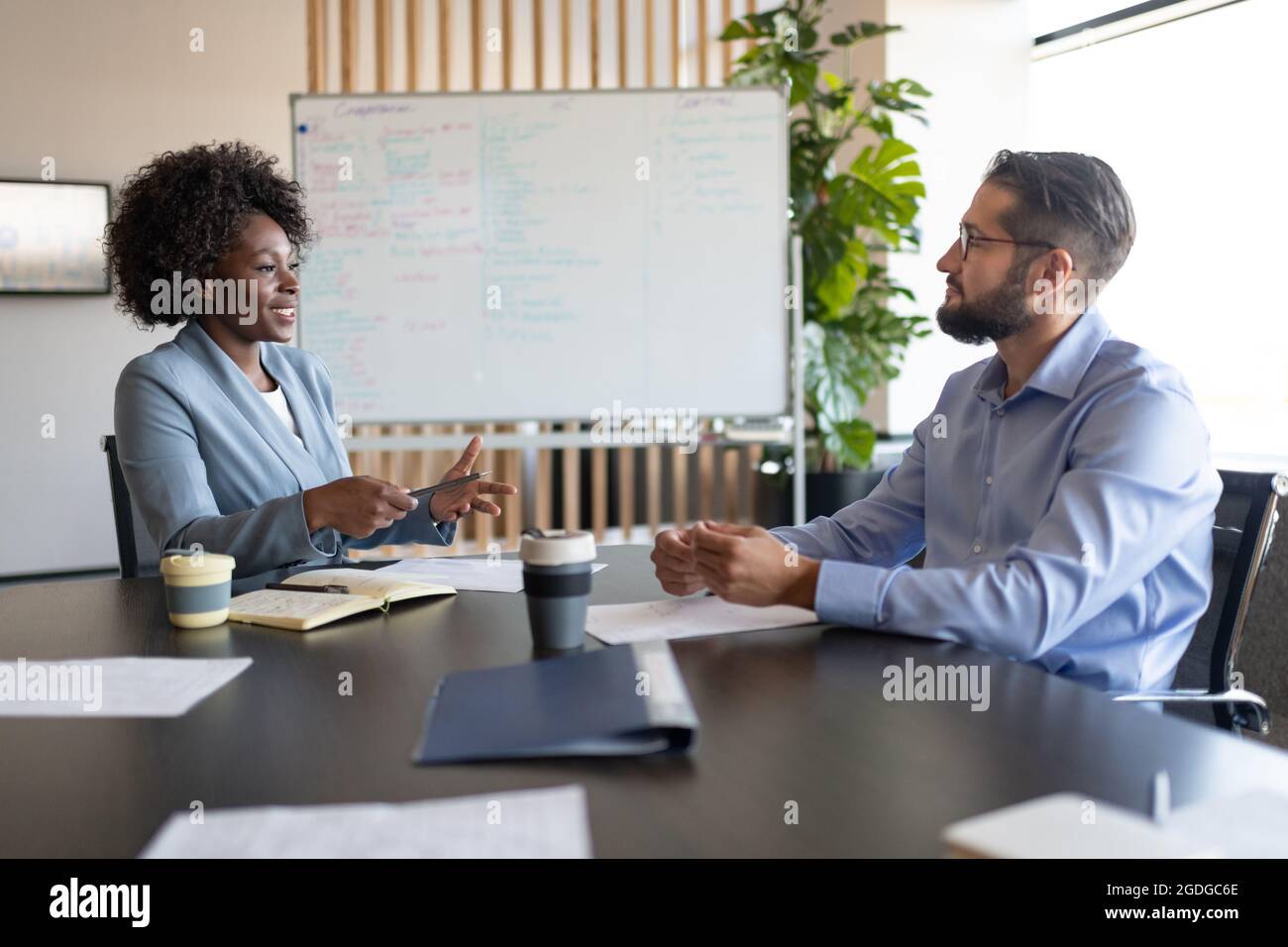 Multirassische Männer und Frauen diskutieren Geschäftspläne am Tisch im Sitzungssaal Stockfoto