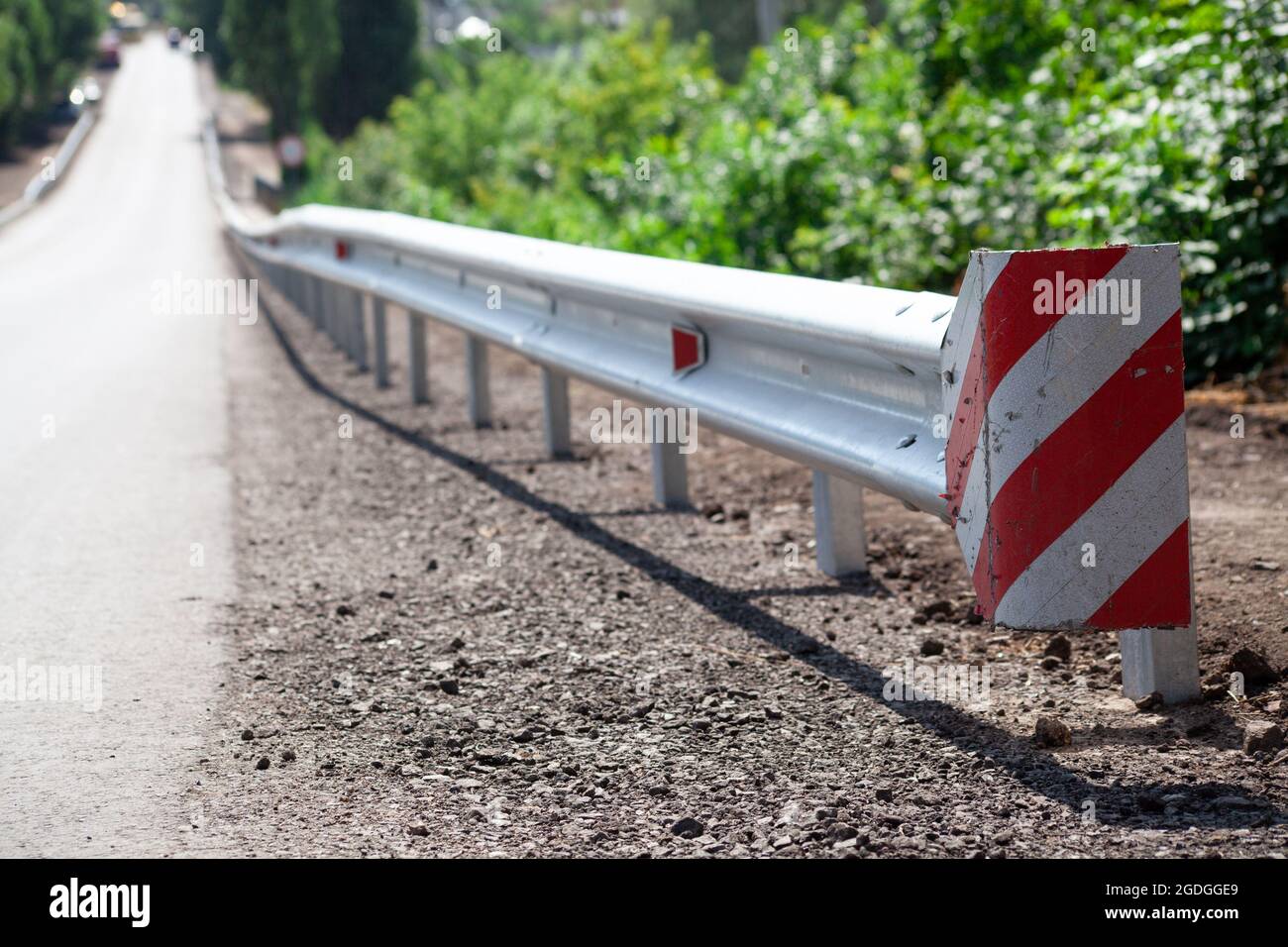 Rote Straßenreflektoren entlang der Straße. Metalleinzäunung von Barriere-Typ, Nahaufnahme. Straßen- und Verkehrssicherheit. Reflektierende Farbe auf dem Schild. Mittlere Barriere Stockfoto