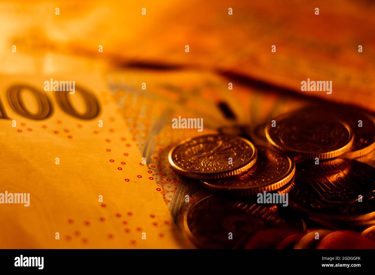 Nahaufnahme von Münzen und Banknoten, die auf einer mit hellem Licht beleuchteten Oberfläche verstreut sind Stockfoto